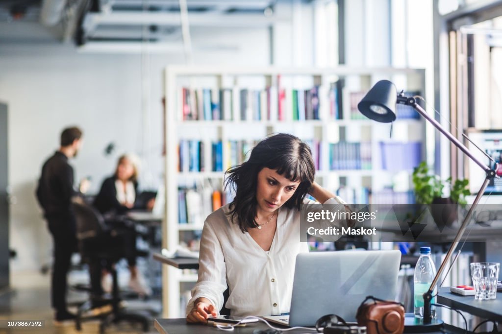 Businesswoman looking at laptop while sitting in office