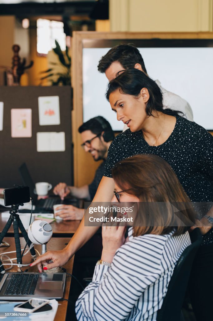 Mid adult businesswoman discussing with team over laptop in office