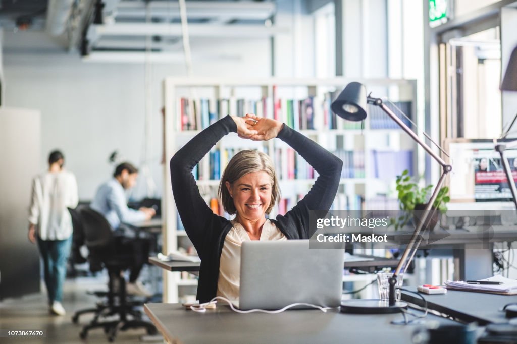 Smiling businesswoman looking at laptop while sitting in office