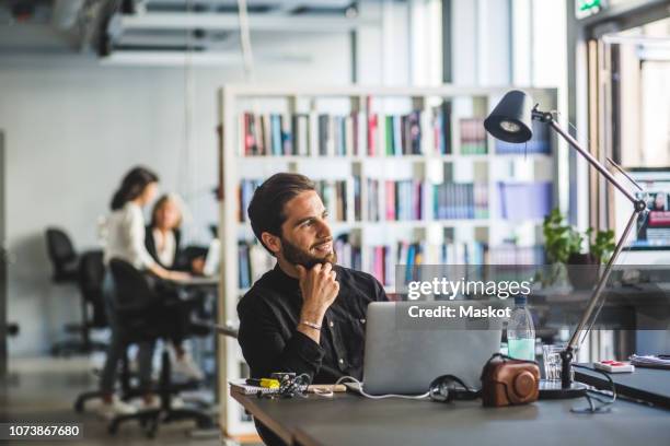 confident businessman looking away while sitting at desk in office - looking away stock pictures, royalty-free photos & images