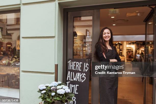 portrait of smiling saleswoman standing at doorway in boutique - saleswoman stock pictures, royalty-free photos & images