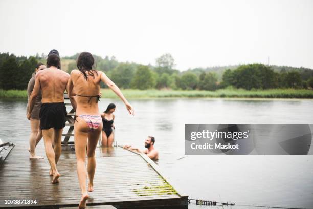 carefree male and female friends enjoying at jetty and lake during weekend getaway - jetty lake stock pictures, royalty-free photos & images