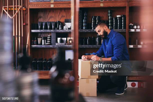 salesman kneeling while writing on paper by rack in deli - cosmetics box stock pictures, royalty-free photos & images