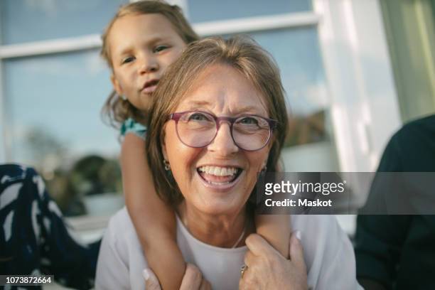 happy senior woman piggybacking granddaughter at porch - ritratto nonna cucina foto e immagini stock