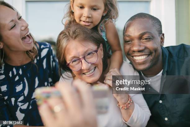 cropped image of man showing mobile phone to happy family on porch - child and unusual angle stock-fotos und bilder