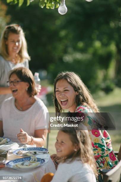 happy girl having lunch with mother and grandmother at table during garden party - standing table outside stock pictures, royalty-free photos & images