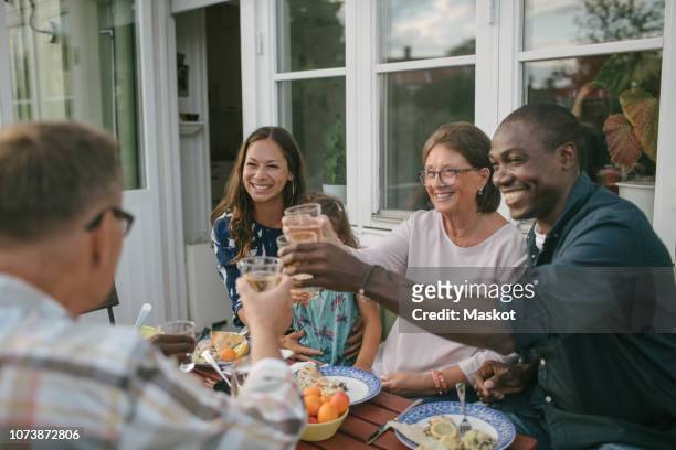 happy multi-generation family toasting drinks at table during garden party - dinner on the deck stock pictures, royalty-free photos & images