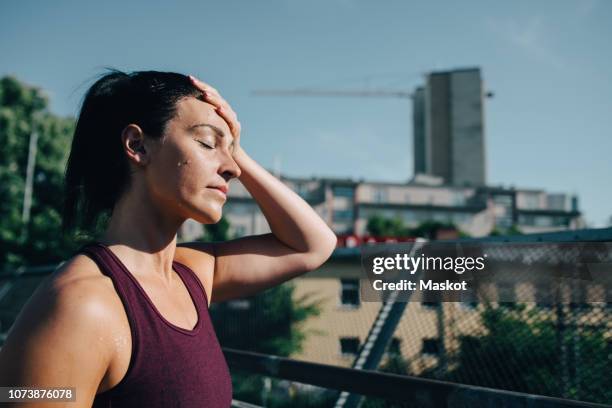 exhausted sportswoman wiping sweat on forehead during sunny day - sudor fotografías e imágenes de stock