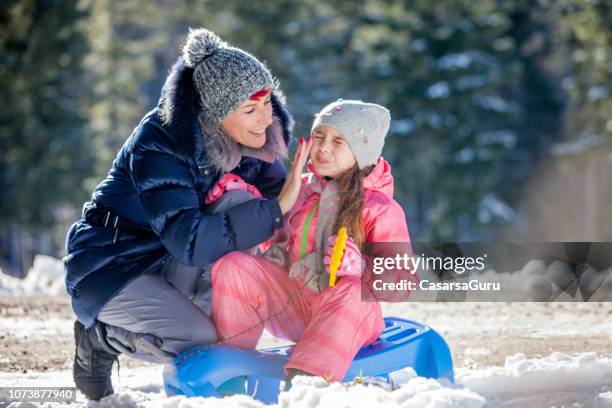 mother applying skin cream to her daughter for protection from the cold - winter skin stock pictures, royalty-free photos & images