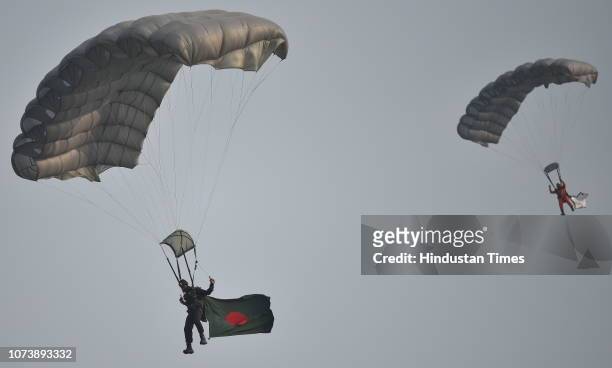 An Army paratrooper carries Bangladesh flag while glides with parachute during Military Tattoo show, at Royal Calcutta Turf Club on December 14, 2018...