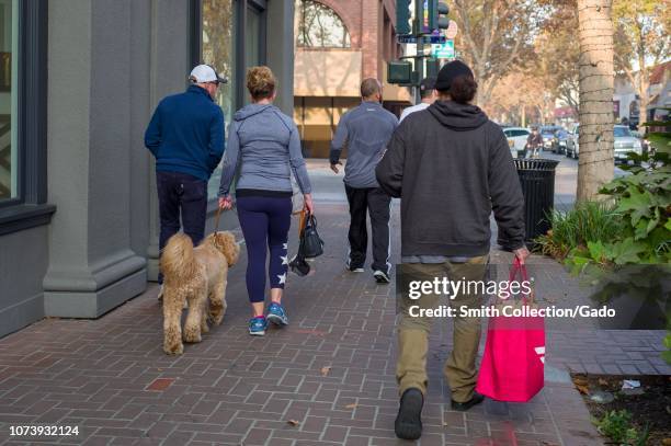 Gig economy worker walks down University Avenue in the Silicon Valley town of Palo Alto, California, carrying the distinctive red bag of food...