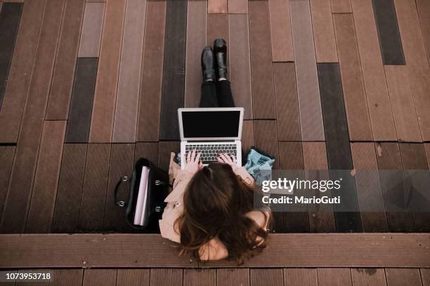 young woman sitting on public park with laptop - college for creative studies stock pictures, royalty-free photos & images