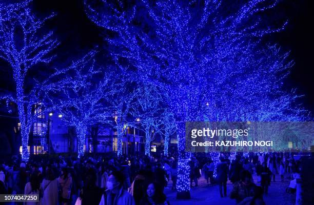 People walk under winter illuminations featuring a theme of 'Blue Cave' at Yoyogi Park in Tokyo on December 16, 2018.