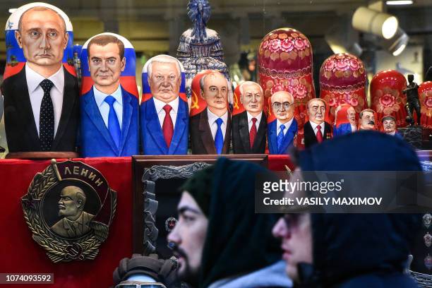 People walks past traditional Russian matryoshka dolls bearing Russian an Soviet leaders Vladimir Putin, Dmitry Medvedev, Boris Yeltsin, Mikhail...