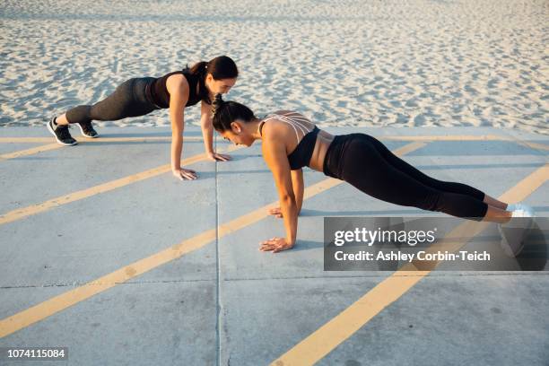 friends doing exercises by beach - plank exercise stockfoto's en -beelden