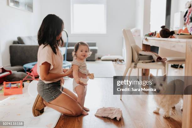 woman changing clothes on toddler daughter - nappy change stock pictures, royalty-free photos & images