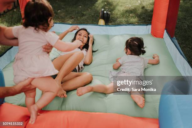 mother and daughters playing on bouncy castle - bouncy castle stock pictures, royalty-free photos & images