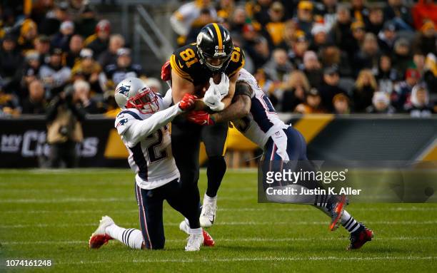 Jesse James of the Pittsburgh Steelers runs up field as Patrick Chung of the New England Patriots and J.C. Jackson attempt a tackle in the first half...