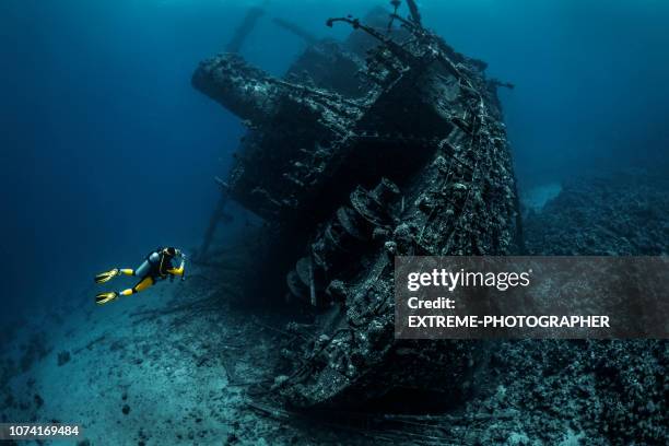 taucher, die beobachtung einer großen havarie völlig verrostet und überwachsen liegen unter wasser im roten meer - shipwreck stock-fotos und bilder