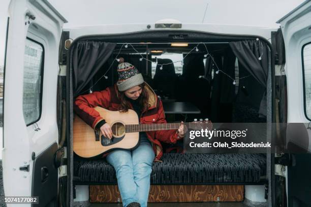 woman playing guitar  in camper van - musician stock pictures, royalty-free photos & images