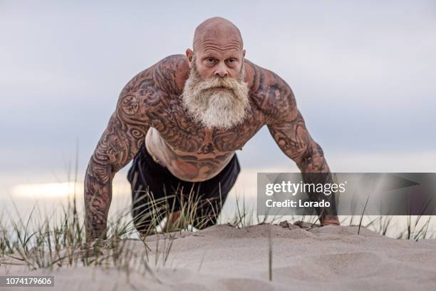 tattooed senior man during workout - muscle men at beach stock pictures, royalty-free photos & images