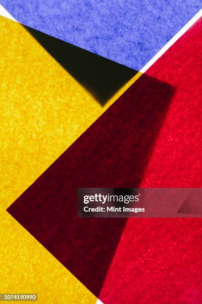 overlapping pieces of multi-coloured construction paper on illuminated backdrop. - yellow construction paper texture stock pictures, royalty-free photos & images