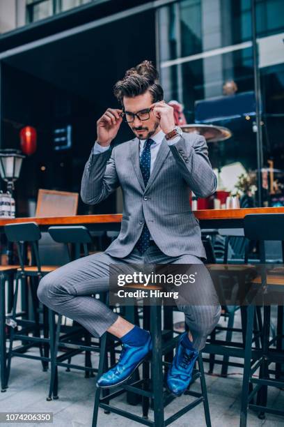 man in suit sitting on bar stool - mens hair model stock pictures, royalty-free photos & images