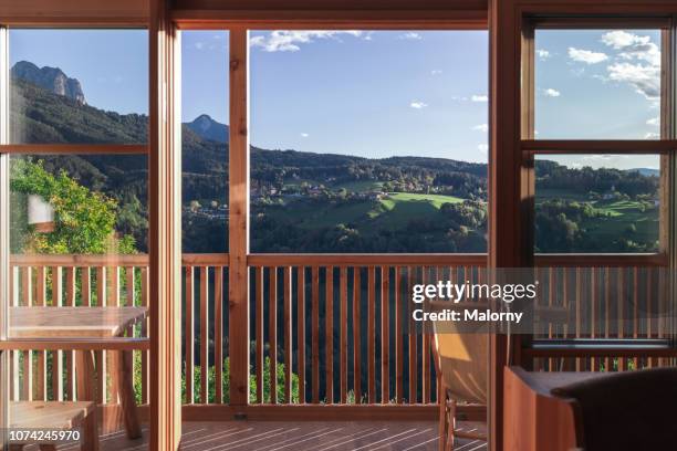 view through the window at a green valley overgrown with forest and mountain range in the background. - hotel balcony stock-fotos und bilder