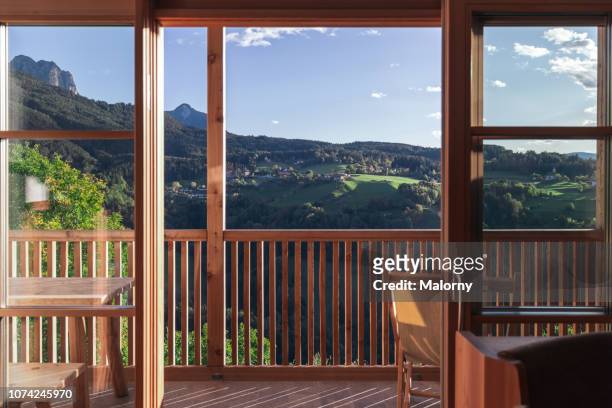 view through the window at a green valley overgrown with forest and mountain range in the background. - balcony view stockfoto's en -beelden