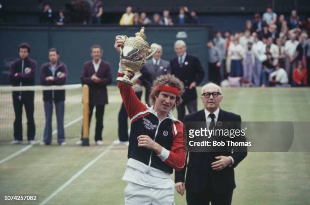 American tennis player John McEnroe holds up the Gentlemen's Singles Trophy after defeating Bjorn Borg of Sweden, 4-6, 7-6, 7-6, 6-4 in the final of...
