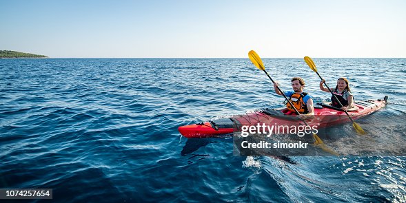 Kayakers rowing together in sea Kayakers rowing together in sea