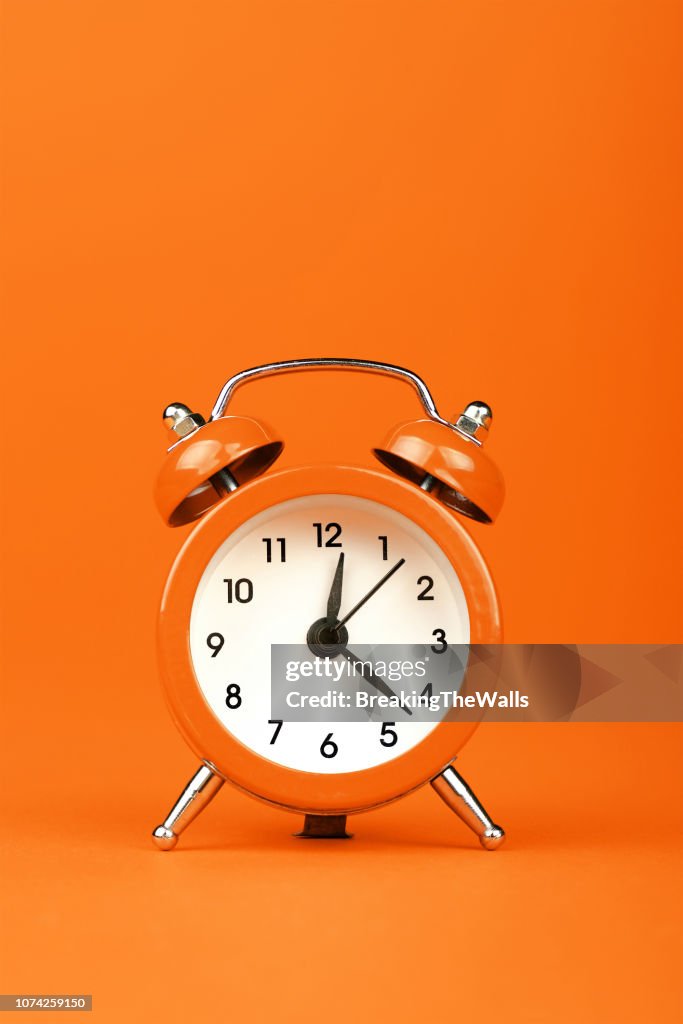 Primer plano del despertador sobre fondo naranja