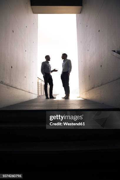 two businessmen talking in a passageway - 2 businessmen in silhouette stock pictures, royalty-free photos & images