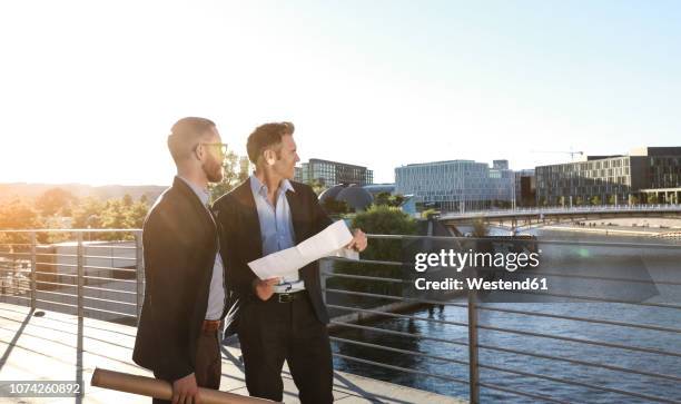 two architects with blueprint standing on a bridge in the city - businessman looking at map stock pictures, royalty-free photos & images