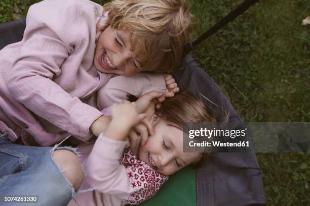 brother and his little sister rampaging in the garden - tickling stock-fotos und bilder