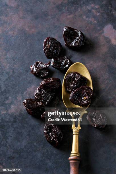 prunes on a vintage brass spoon - dörrpflaume stock-fotos und bilder