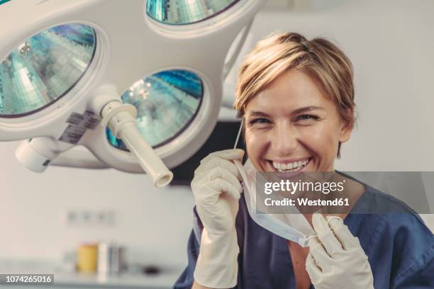 dental surgeon removing surgical mask, portrait - dentista imagens e fotografias de stock