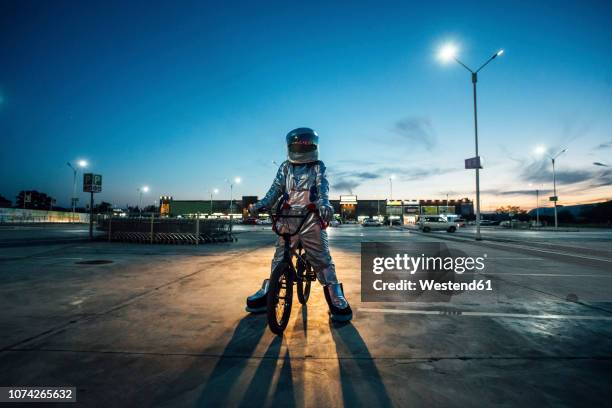 spaceman in the city at night on parking lot with bmx bike - sport laden stock-fotos und bilder