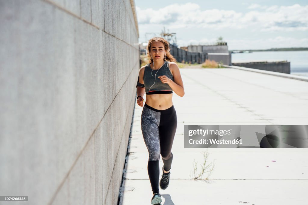 Young athletic woman running along a wall