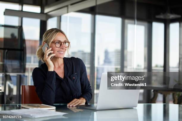 businesswoman sitting in office, talking on the phone - phone business stock-fotos und bilder