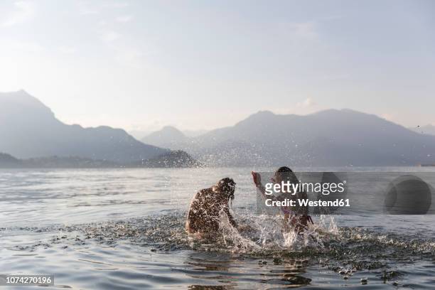 happy young couple playing in a lake - lake como stock-fotos und bilder