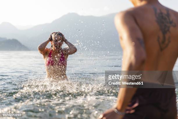 happy young couple playing in a lake - back tattoo stock pictures, royalty-free photos & images