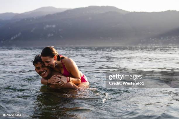 happy playful young couple in a lake - province de côme italie photos et images de collection