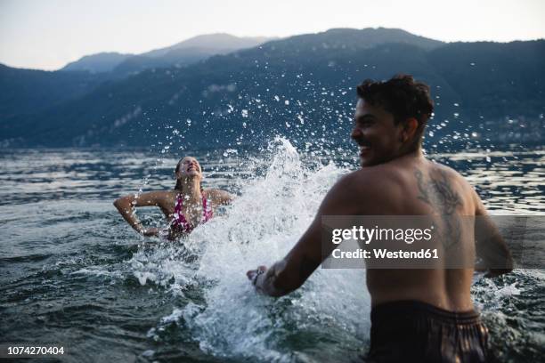 happy young couple playing in a lake - landscape tattoo stock pictures, royalty-free photos & images