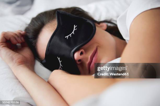 portrait of young woman with sleep mask in bed - brunette woman bed stock pictures, royalty-free photos & images