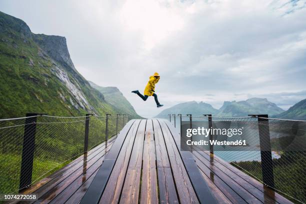 norway, senja island, man jumping on an observation deck at the coast - euforie stockfoto's en -beelden