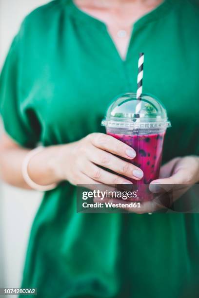 woman's hands holding plastic cup of pink smoothie, close-up - smoothie close up textfreiraum stock-fotos und bilder