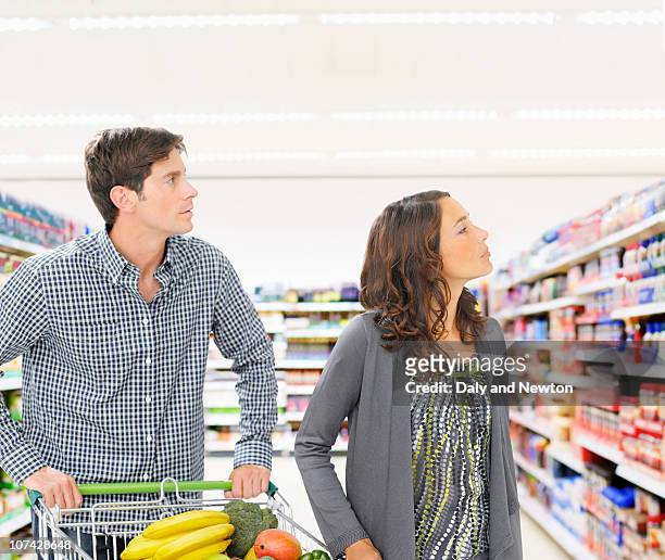 boy holding bag full of fruits and vegetables in grocery store - frau einkaufswagen ernst stock-fotos und bilder