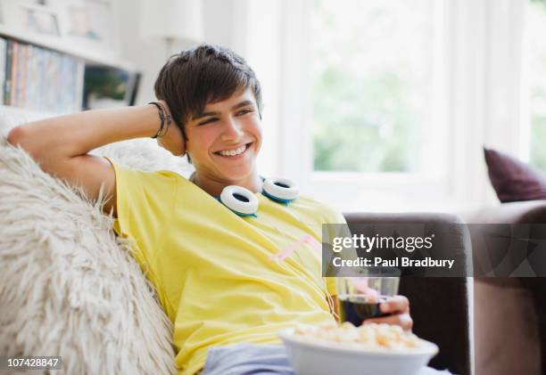 smiling teenage boy sitting with popcorn and soda - leaning stock pictures, royalty-free photos & images