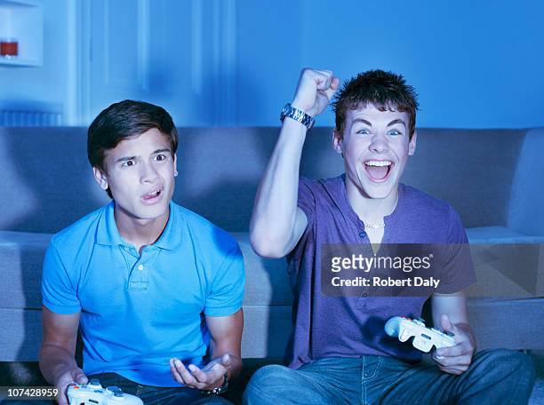 smiling teenage boys playing video game - delusione foto e immagini stock